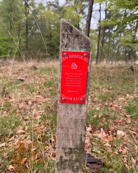Rood routebordje op een houten paal